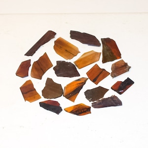 May include: A white box with a circular design made of small, irregular pieces of brown, red, and orange tiger eye stone.