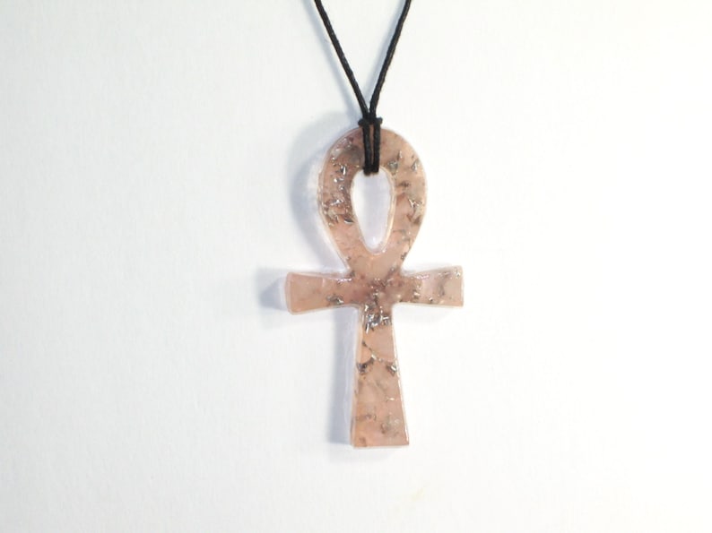 May include: A pink and silver Ankh pendant necklace with a black cord.