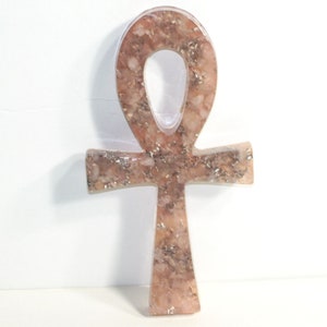 May include: A pink and gold Ankh pendant made of resin with a glittery finish.