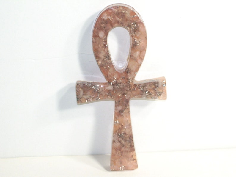 May include: A pink and gold Ankh pendant made of resin with a glittery finish.