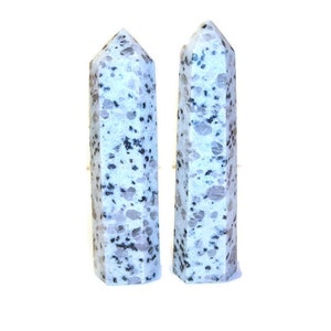 May include: Two tall, polished stone obelisks. The obelisks are white with gray and black speckled patterns. They have a faceted design and a pointed top. The background is plain white.