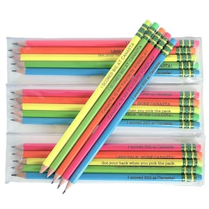 May include: A pack of ten neon colored pencils with green and white striped erasers. Each pencil has a different saying about the card game Canasta printed on it. The sayings include "I scored big at Canasta", "Canasta is my favorite foreplay", "Less talk more Canasta", and "Got your back when you pick the pack".