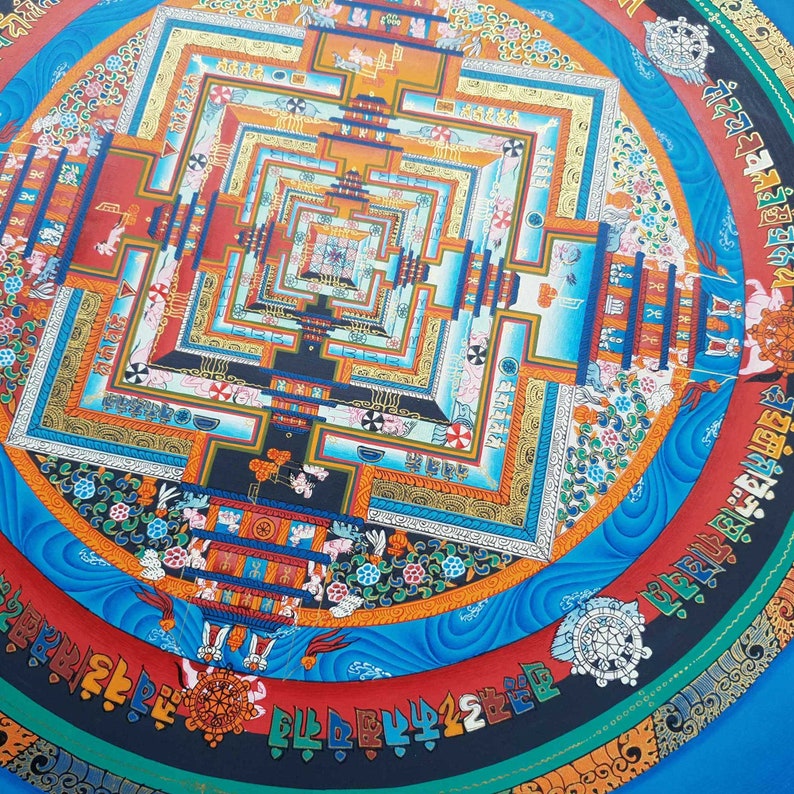 May include: A colourful mandala with a blue background and intricate patterns in shades of red, orange, yellow, green, and black. The mandala features a central square with concentric squares radiating outwards, creating a mesmerising optical illusion.