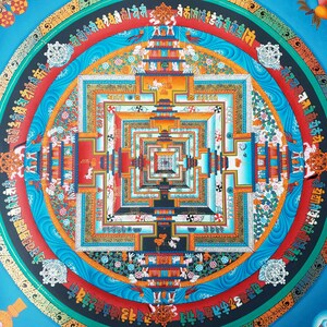 May include: A colourful mandala with a square design in the centre. The mandala is surrounded by a circle of text in a foreign language. The colours are vibrant and include blue, red, yellow, and green.