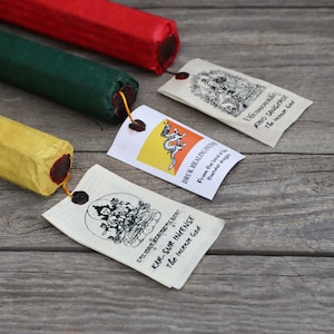May include: Three incense sticks wrapped in yellow, green, and red paper with labels that read "Kar-Sur Incense The Incense God", "Druk Healing Incense From the land of thunder draga", and "Rino Sangchoe The Incense God".