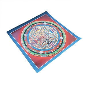 May include: A colorful mandala print on canvas with a blue border. The mandala features intricate details and patterns in shades of red, blue, green, and yellow.