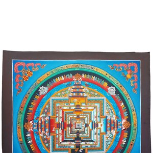 May include: A colourful mandala with a blue background and intricate details. The mandala is surrounded by a border of Tibetan script. The mandala is a symbol of the universe and is often used in meditation.