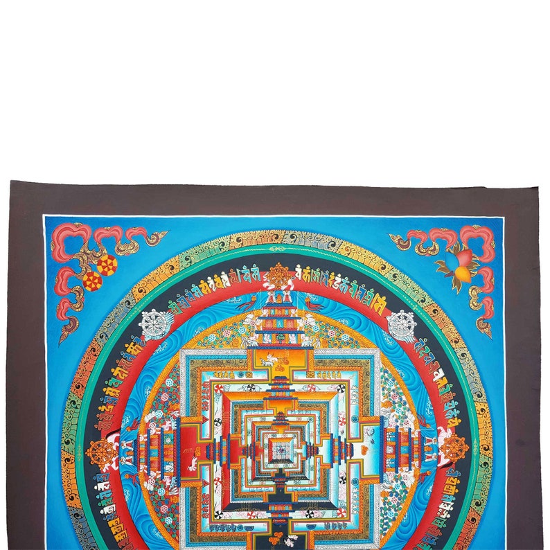 May include: A colourful mandala with a blue background and intricate details. The mandala is surrounded by a border of Tibetan script. The mandala is a symbol of the universe and is often used in meditation.