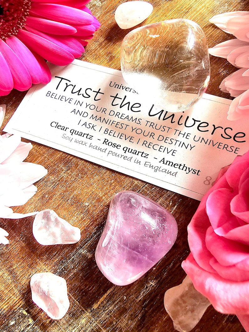 May include: A set of three crystals, clear quartz, rose quartz, and amethyst, with a card that reads "Trust the Universe. Believe in your dreams, trust the universe and manifest your destiny. I ask, I believe, I receive. Clear quartz - Rose quartz - Amethyst. Soy wax hand poured in England."