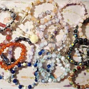 May include: A collection of numerous beaded bracelets featuring a variety of colours, including orange, blue, pink, white, and black. The bracelets are crafted with round beads, some with metallic accents, leopard print patterns, and small charms.