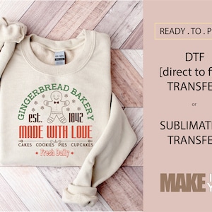 May include: A beige sweatshirt with a gingerbread man graphic and the text "Gingerbread Bakery est. 1842 Made With Love Cakes Cookies Pies Cupcakes *Fresh Daily*" printed on the front.