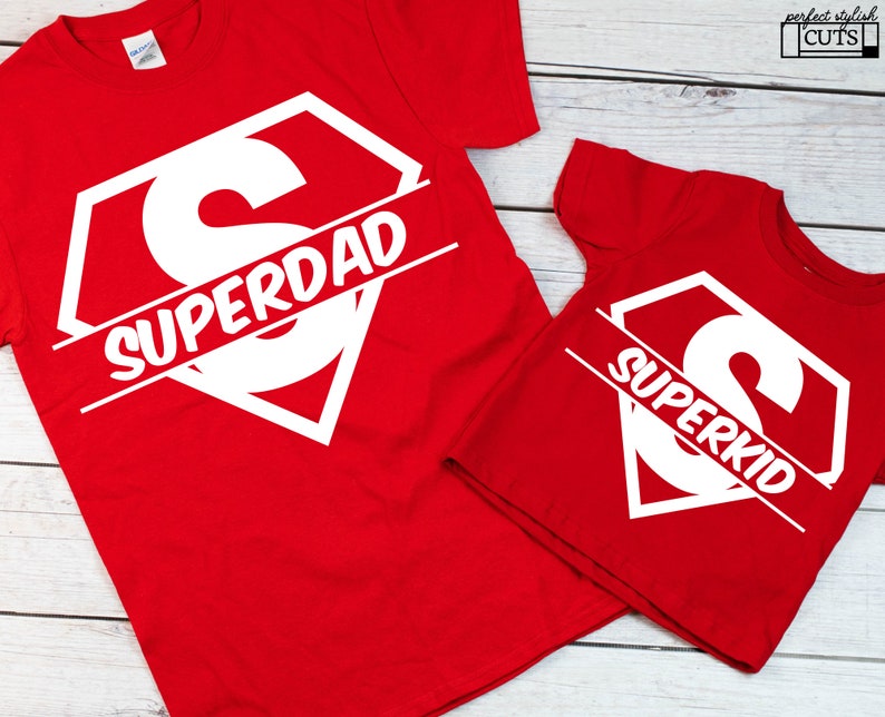 May include: Two red t-shirts with a white superhero logo and the words "Superdad" and "Superkid" printed on them.