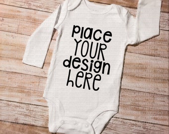 Puede incluir: Un body blanco de manga larga para bebé con el texto "Place your design here" en negro.