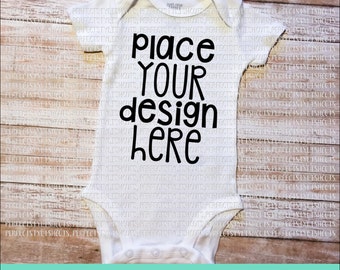 Puede incluir: Un body blanco para bebé con texto negro que dice "Coloque su diseño aquí".