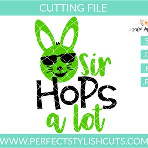 以下が含まれることがあります： サングラスをかけた緑色のウサギの顔に、黒い文字で「Sir Hops a lot」と書かれています。
