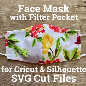 May include: Floral face mask with a filter pocket. The mask has a white background with red, yellow, and green floral patterns. Text reads "Face Mask with Filter Pocket" and "for Cricut & Silhouette SVG Cut Files".