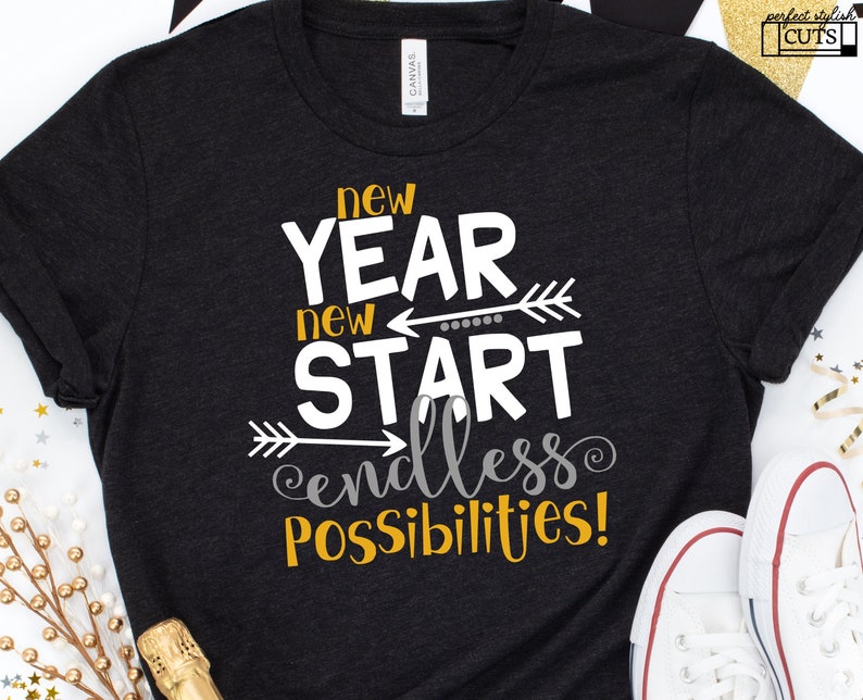 Pu&ograve; includere: Maglietta nera con testo bianco che recita "new year new start endless possibilities!" con frecce e punti dorati.