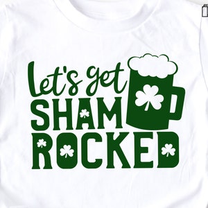 May include: White t-shirt with green text that reads "Let's get shamrocked" with a green beer mug and shamrock graphic.