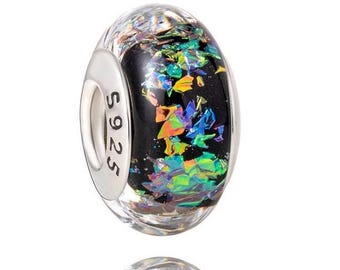 May include: A round glass charm bead featuring a black core embedded with iridescent, multi-colored foil flakes that shimmer in shades of green, blue, and orange. The bead has a polished silver-tone metal core stamped with the text S925.