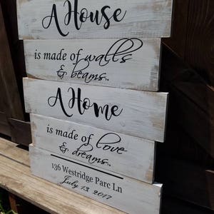 May include: A white wooden sign with black lettering that reads "A House is made of walls & beams. A Home is made of love & dreams." The sign also includes the address "136 Westridge Parc Ln" and the date "July 13, 2017".