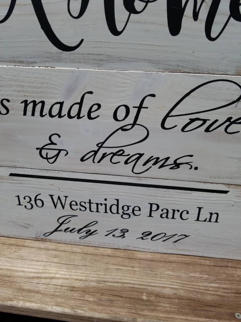 May include: A white wooden sign with black lettering that reads "Home is made of love & dreams." The sign also includes the address "136 Westridge Parc Ln" and the date "July 13, 2017".
