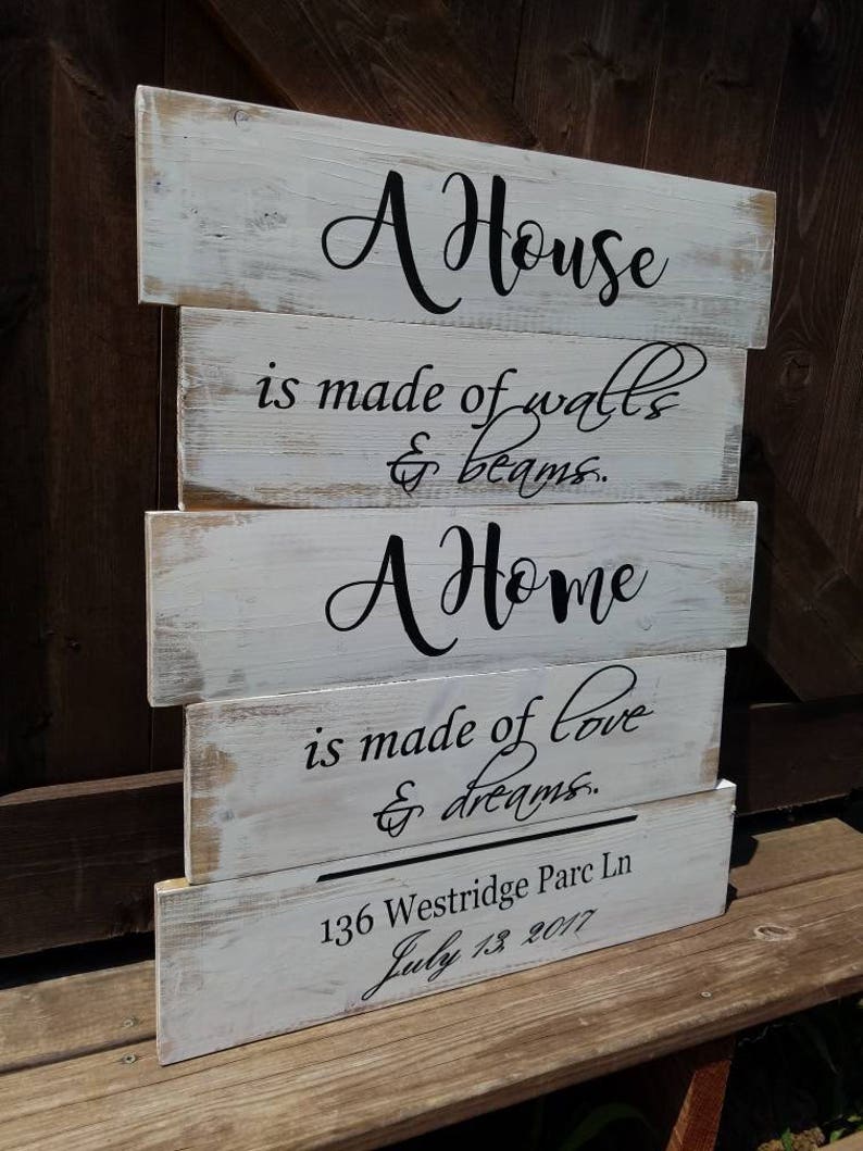 May include: Whitewashed wooden sign with black lettering that reads "A House is made of walls & beams. A Home is made of love & dreams. 136 Westridge Parc Ln July 13 2017"