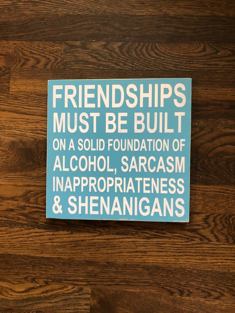 May include: A blue wooden sign with white text that reads "Friendships must be built on a solid foundation of alcohol, sarcasm, inappropriateness & shenanigans."