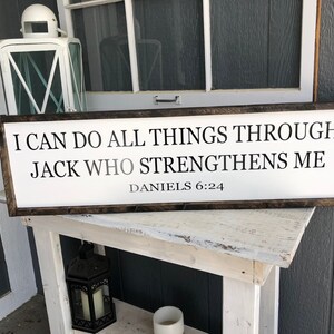 Op de afbeelding: Een wit houten bord met zwarte tekst die luidt: "Ik kan alles door Jack doen die mij sterkt Dani&euml;l 6:24".