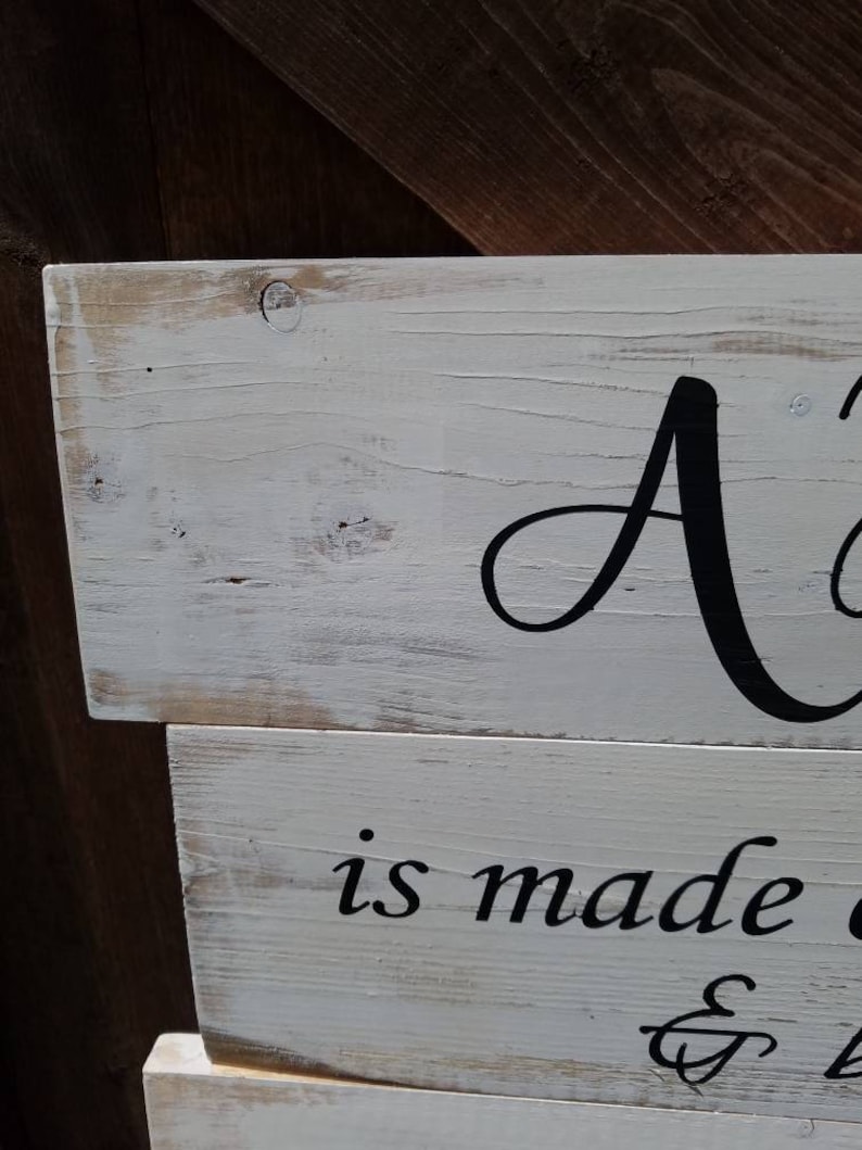 May include: A white wooden sign with black lettering that reads "A home is made with love & laughter".