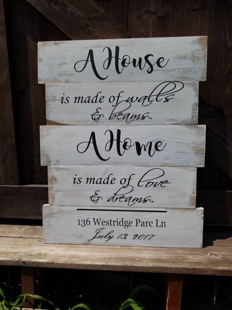 May include: A white wooden sign with black lettering that reads "A House is made of walls & beams. A Home is made of love & dreams." The sign also includes the address "136 Westridge Parc Ln" and the date "July 13, 2017".