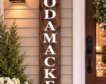 May include: A tall, rectangular wooden sign with a dark brown stained finish and visible wood grain. The word "The" is printed in white at the top, followed by the vertical white text "RODAMACKERS" in a bold, serif font centered on the board.