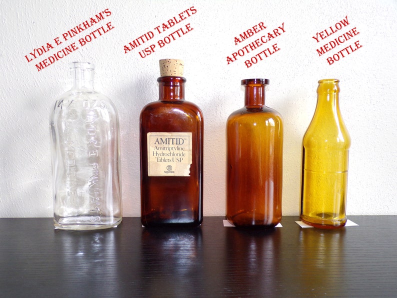 May include: Four glass bottles of different colors and shapes. The bottles are labeled with the text "Lydia E Pinkham's Medicine Bottle", "Amitriptyline Hydrochloride Tablets USP Bottle", "Amber Apothecary Bottle", and "Yellow Medicine Bottle".