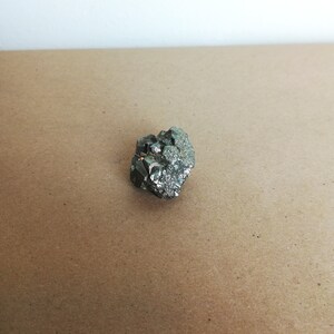 May include: A cluster of pyrite crystals, also known as fool's gold, with a metallic silver and gold color. The crystals are arranged in a random pattern and have a rough, textured surface.