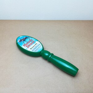 May include: A green beer tap handle with an oval top featuring a graphic of a moose and the text Moose Drool Brown Ale Big Sky Brewing Missoula, Montana. The handle has a smooth, glossy finish and a rounded, ergonomic grip for easy operation.