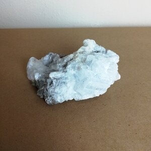 May include: A large, white, crystalline rock with a rough, textured surface. The rock has a cluster of crystals that are arranged in a random pattern.