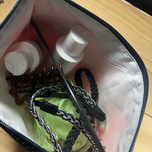 Puede incluir: Una bolsa con cremallera azul y blanca de lunares con un peine negro, cintas para el pelo y pinzas para el pelo en su interior. Tambi&eacute;n hay dos botellas blancas de loci&oacute;n.