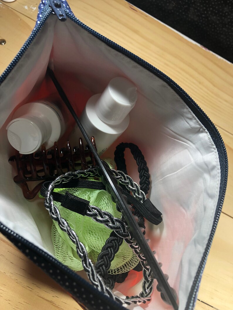 Puede incluir: Una bolsa con cremallera azul y blanca de lunares con un peine negro, cintas para el pelo y pinzas para el pelo en su interior. Tambi&eacute;n hay dos botellas blancas de loci&oacute;n.