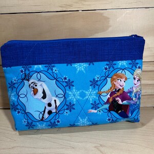 May include: A blue zippered pouch with a quilted design. The pouch features a print of Elsa, Anna, and Olaf from the movie Frozen. The print is on a light blue background with white snowflakes.