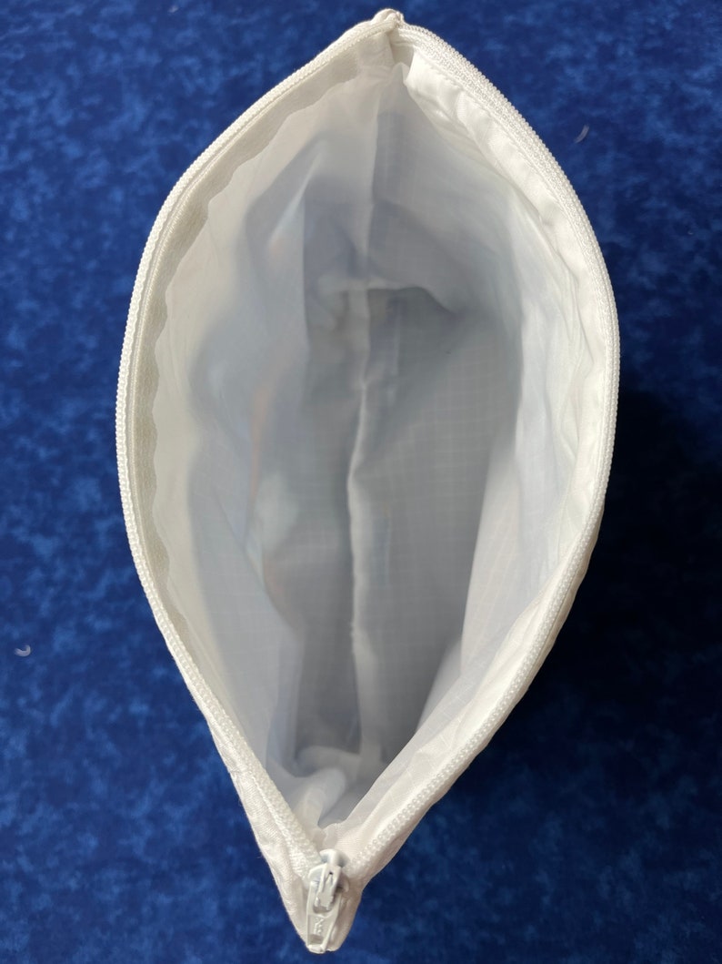 May include: White zippered pouch with a white lining. The pouch is open and the zipper is visible.