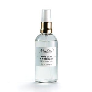 May include: A clear glass bottle with a gold cap and a white spray nozzle. The bottle contains a refreshing mist with aloe vera and rosemary. The label reads "Merlette - Aloe Vera & Rosemary Refreshing Mist 3.4 oz / 100 ml".