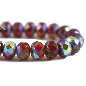 May include: A strand of red iridescent glass beads. The beads are faceted and have a round shape.