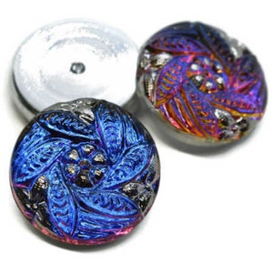 May include: Two iridescent glass buttons with a swirling, floral design. The button on the left is blue and purple, while the button on the right is orange and purple.