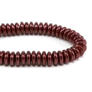 May include: A maroon colored bracelet made of small, round beads. The beads are arranged in a spiral pattern.