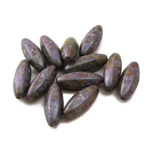 May include: A group of 12 oval-shaped glass beads with a mottled brown and purple iridescent finish.
