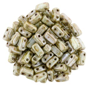 May include: A pile of light green and brown glass beads with two holes each. The beads are rectangular in shape and have a slightly iridescent finish.