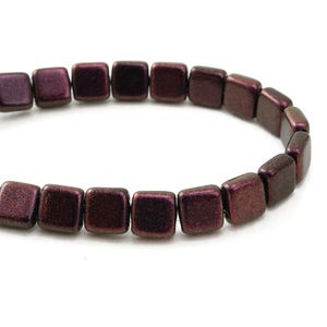 May include: A strand of square beads in a deep burgundy color with a metallic sheen. The beads are evenly sized and strung together, creating a continuous line. The beads are displayed against a white background.