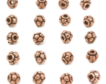 May include: A collection of 18 copper-colored beads with a textured surface. The beads are round and have a small hole in the center.