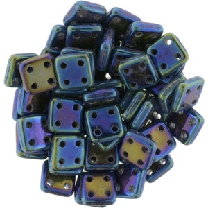 May include: A pile of iridescent blue and green square glass beads with four holes each. The beads are approximately 6mm in size.