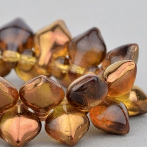 May include: A strand of amber glass beads with a metallic sheen. The beads are faceted and have a teardrop shape.