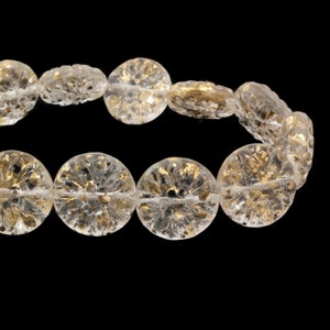 May include: A strand of clear glass beads with gold flecks. The beads are round and have a textured surface.